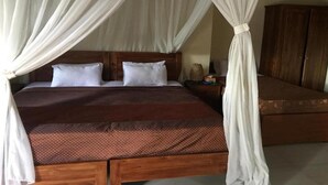 A bed with a wooden headboard, white pillows, and a brown bedspread. - Bali Breeze Bungalows (Ubud)