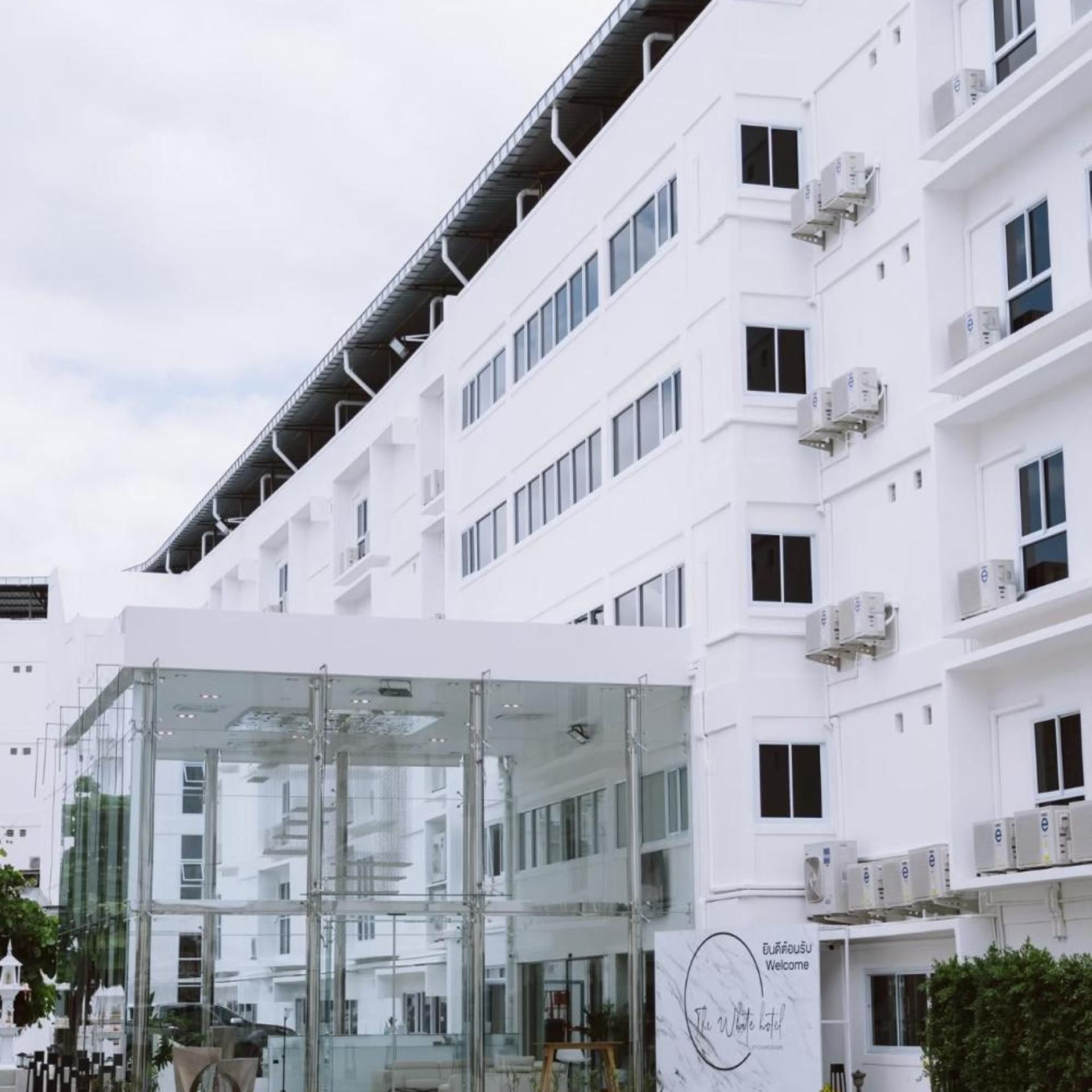A modern hotel building with a glass entrance and multiple air conditioning units on the facade.