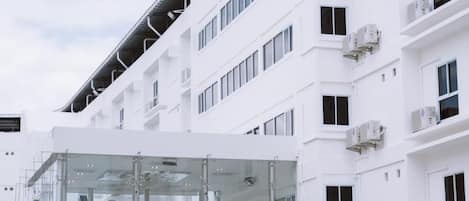 Un hôtel moderne avec une façade en verre et de nombreuses unités de climatisation.