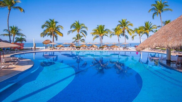 A pool area with clear blue water, surrounded by palm trees and beach umbrellas. - Marival Emotions Resort & Suites Riviera Nayarit by Mercure (Nuevo Nayarit)