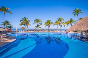 A pool area with clear blue water, surrounded by palm trees and beach umbrellas. - Marival Emotions Resort & Suites Riviera Nayarit by Mercure (Nuevo Nayarit)