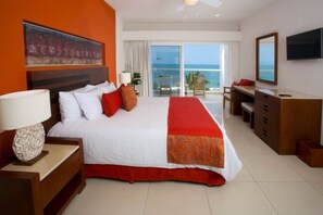 A hotel room with a large bed, a desk, a TV, and a balcony with a view of the ocean. - Marival Emotions Resort & Suites Riviera Nayarit by Mercure (Nuevo Nayarit)