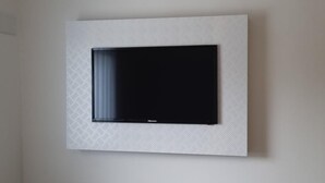 A flat-screen TV mounted on a textured wall. - Check Inn Hotel (Cape Town)