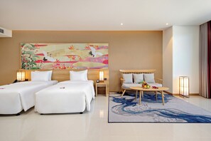 Une chambre d’hôtel avec deux lits, un canapé, une table avec des fruits et un grand tableau au mur.