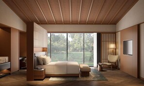 Een moderne slaapkamer met een groot bed, een televisie, een stoel en uitzicht op een tuin.