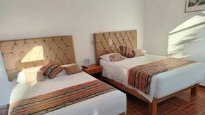 A hotel room with two beds, each with a tufted headboard, white linens, and striped blankets. - Hotel Mexico Lindo (Santa María Huatulco)