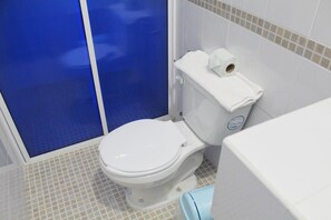 Un baño con inodoro blanco, cabina de ducha azul y lavabo blanco.
