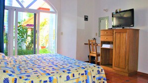 A bedroom with a bed, a television on a wooden cabinet, and a sliding glass door leading to a balcony. - Hotel Mexico Lindo (Santa María Huatulco)
