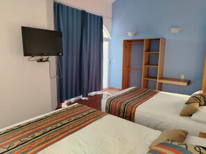 Habitación de hotel con dos camas, televisión, armario y ventana con cortinas.