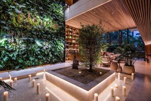 A modern hotel lobby with a vertical garden, a central seating area with candles, and a wooden ceiling. - Elcielo Hotel and Restaurant (Medellín)