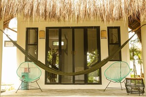 A hammock between two chairs in front of a building with large windows and a thatched roof. - Mi Kasa Tu Kasa By Nah Hotels (Bacalar)