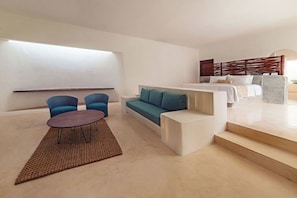 Ein modernes Wohnzimmer mit einer Couch, zwei Sesseln, einem Couchtisch und einer Treppe, die zu einem Schlafzimmer führt.