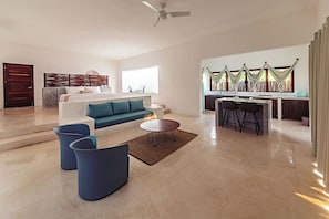 A spacious living area with a sofa, coffee table, and chairs, a dining area with a table and chairs, and a kitchen with a window and curtains. - Mi Kasa Tu Kasa By Nah Hotels (Bacalar)