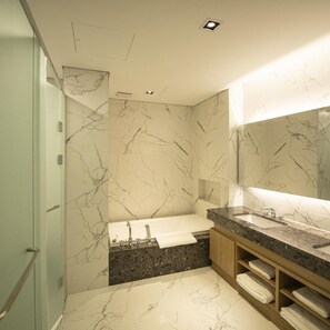 A modern bathroom with a marble wall, a large mirror, a bathtub, and a granite countertop. - J-one Hotel and Resort (Cheongju)