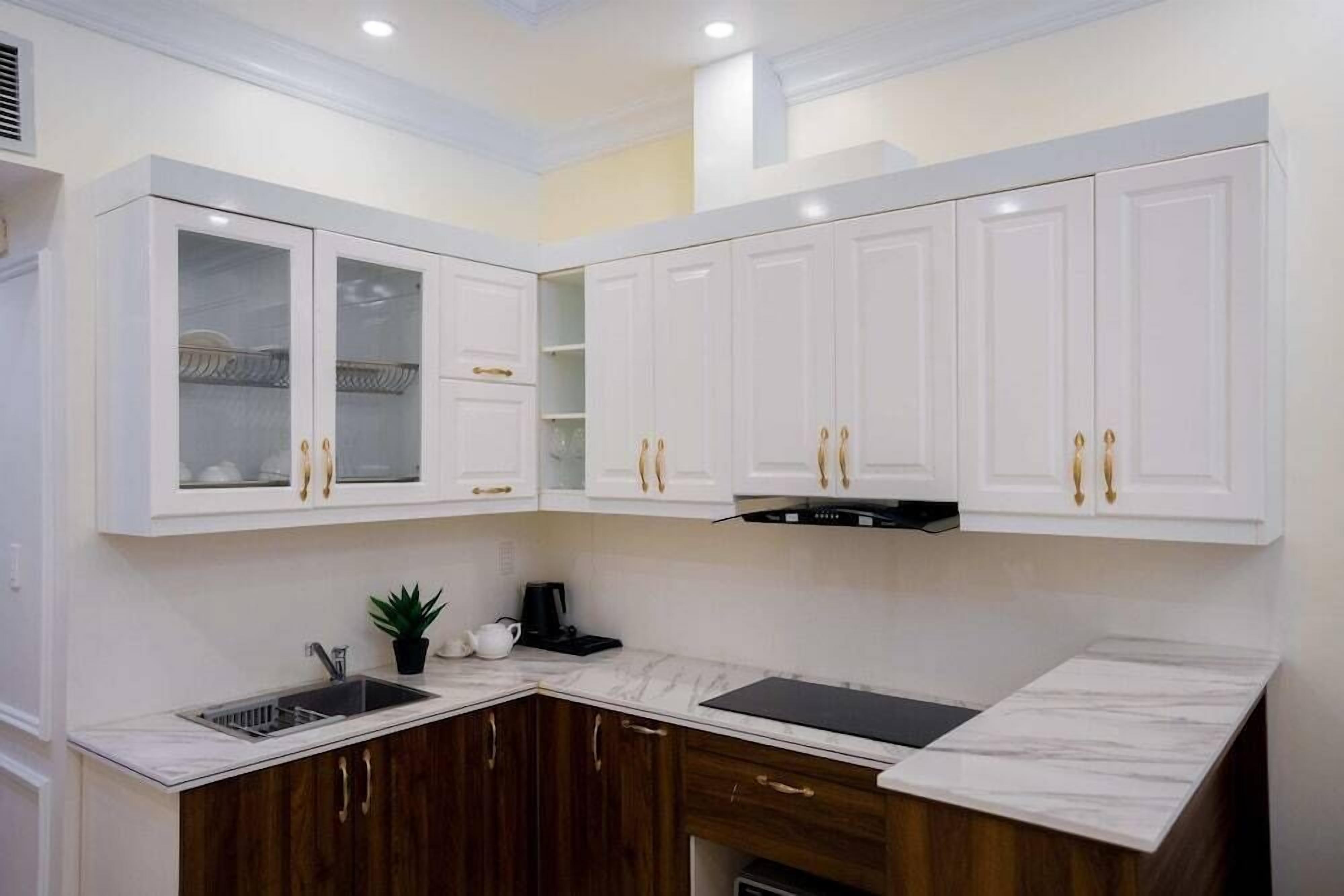 A modern kitchen with white cabinets, a marble countertop, and a built-in stove.