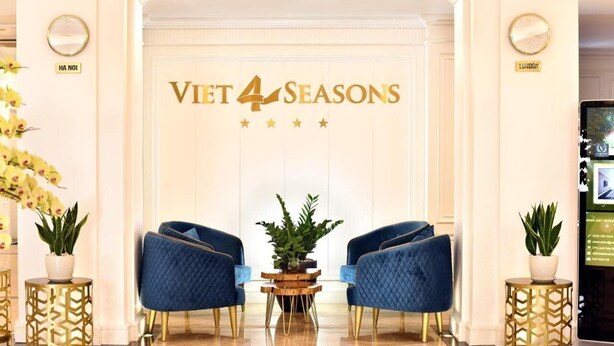 A reception area with a sign reading "Viet 4 Seasons" and two blue armchairs with gold legs. - Viet 4 Seasons Hotel (Hai Phong)