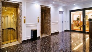 A hotel lobby with marble flooring, three elevator doors, and a dining area visible through a glass partition. - Viet 4 Seasons Hotel (Hai Phong)