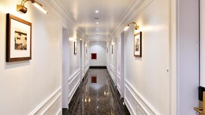A long, narrow hallway with white walls and marble flooring, featuring framed pictures and wall sconces. - Viet 4 Seasons Hotel (Hai Phong)