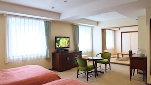 A hotel room with two beds, a TV, a desk, and a chair.
