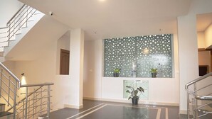 A modern interior with a staircase, a glass wall with a polka dot pattern, and potted plants.