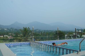 A swimming pool with a view of mountains and greenery in the background. - Blue Vista Residancy (Kalpetta)