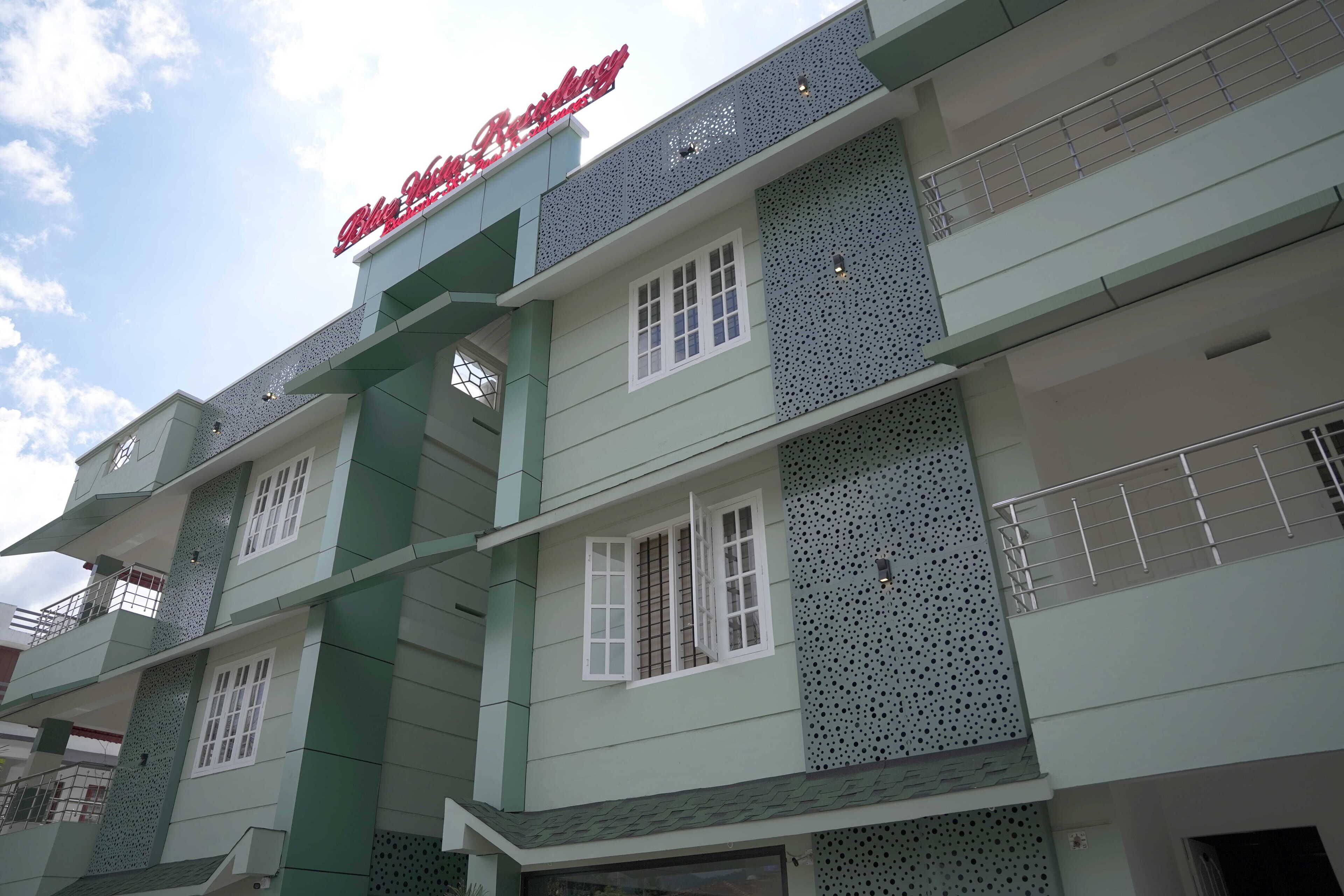 Un edificio de varios pisos con una combinación de colores verde y blanco, con balcones con barandillas metálicas y un letrero que dice "Blue Star College".