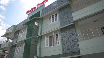 Un edificio de varios pisos con una combinación de colores verde y blanco, con balcones con barandillas metálicas y un letrero que dice "Blue Star College".