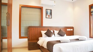 A hotel room with a wooden bed, white bedding, and a large window with blinds.