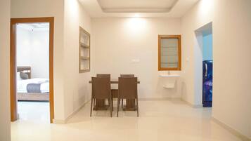 A hotel room with a dining area, a bed, a bathroom, and a view of the outside.