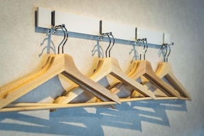 Des cintres en bois fixés sur un porte-cintres mural.