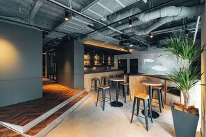 Un espace bar moderne avec des tabourets, un comptoir et une grande plante en pot.