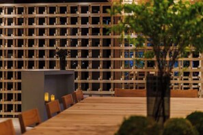 A restaurant with a long wooden table and chairs, a wooden partition wall, and a potted plant in the foreground. - Doyanen Hotels Bakuro (Osaka)
