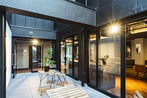 A modern interior with a wooden floor, glass doors, and a dining area with a table and chairs. - Doyanen Hotels Bakuro (Osaka)
