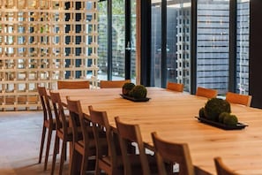 Un salón de conferencias con una larga mesa de madera, varias sillas y una estructura de celosía de madera decorativa.