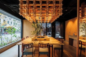 Un comedor moderno con una amplia mesa de madera, sillas y una estructura colgante de madera.