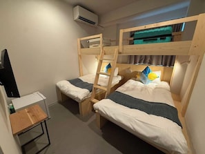 Une chambre de dortoir équipée de lits superposés, d’un bureau et d’un appareil de climatisation.