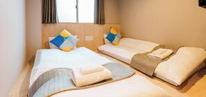 A hotel room with two single beds, each with a pillow and a folded towel. - Doyanen Hotels Bakuro (Osaka)