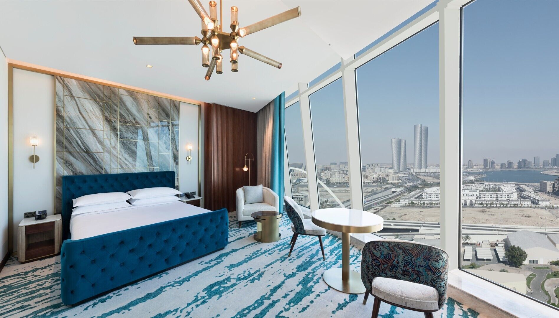 Habitación de hotel moderna con una cama grande, zona de estar y vistas a la ciudad.