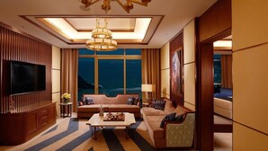 A spacious living room with a large flat-screen TV, comfortable seating, a coffee table, and a view of the ocean through large windows. - Royal M Resort Al Aqah Beach Resort (Al Aqah)