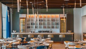 A modern restaurant with a bar area, multiple seating options, and a well-lit interior. - Royal M Resort Al Aqah Beach Resort (Al Aqah)