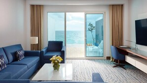 A hotel room with a blue sofa, a coffee table with flowers, a TV, and a balcony with a view of the sea. - Royal M Resort Al Aqah Beach Resort (Al Aqah)
