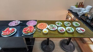 A buffet table with various dishes including watermelon slices, salads, and other food items. - Sazi Resin Hotel - Free Nails/hairwash (Ho Chi Minh City)