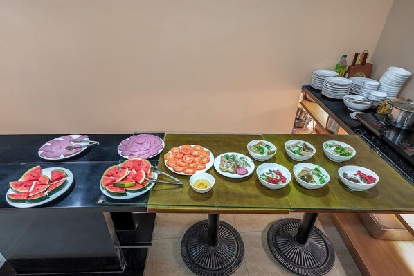 Ein reichhaltiges Buffet mit verschiedenen Speisen, darunter Wassermelonenscheiben, Salate und weitere Gerichte.