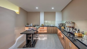 A modern kitchen with a central island, wooden cabinets, and a black countertop. - Sazi Resin Hotel - Free Nails/hairwash (Ho Chi Minh City)