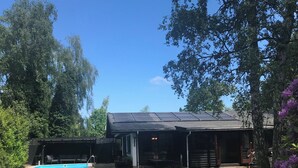 A backyard with a trampoline, a pool, a covered patio, and a wooden deck. - Holiday home, swimmingpool and beach (Nykøbing Sj)