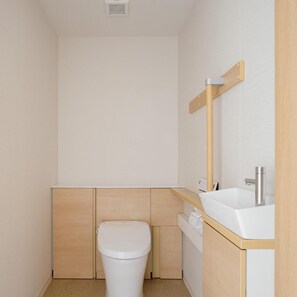 Une petite salle de bain moderne, équipée de toilettes, d’un lavabo et d’un miroir.