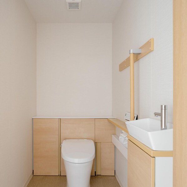 A small, modern bathroom with a toilet, sink, and mirror. - Hotel Mid in Kuramae Ekimae (Tokyo)