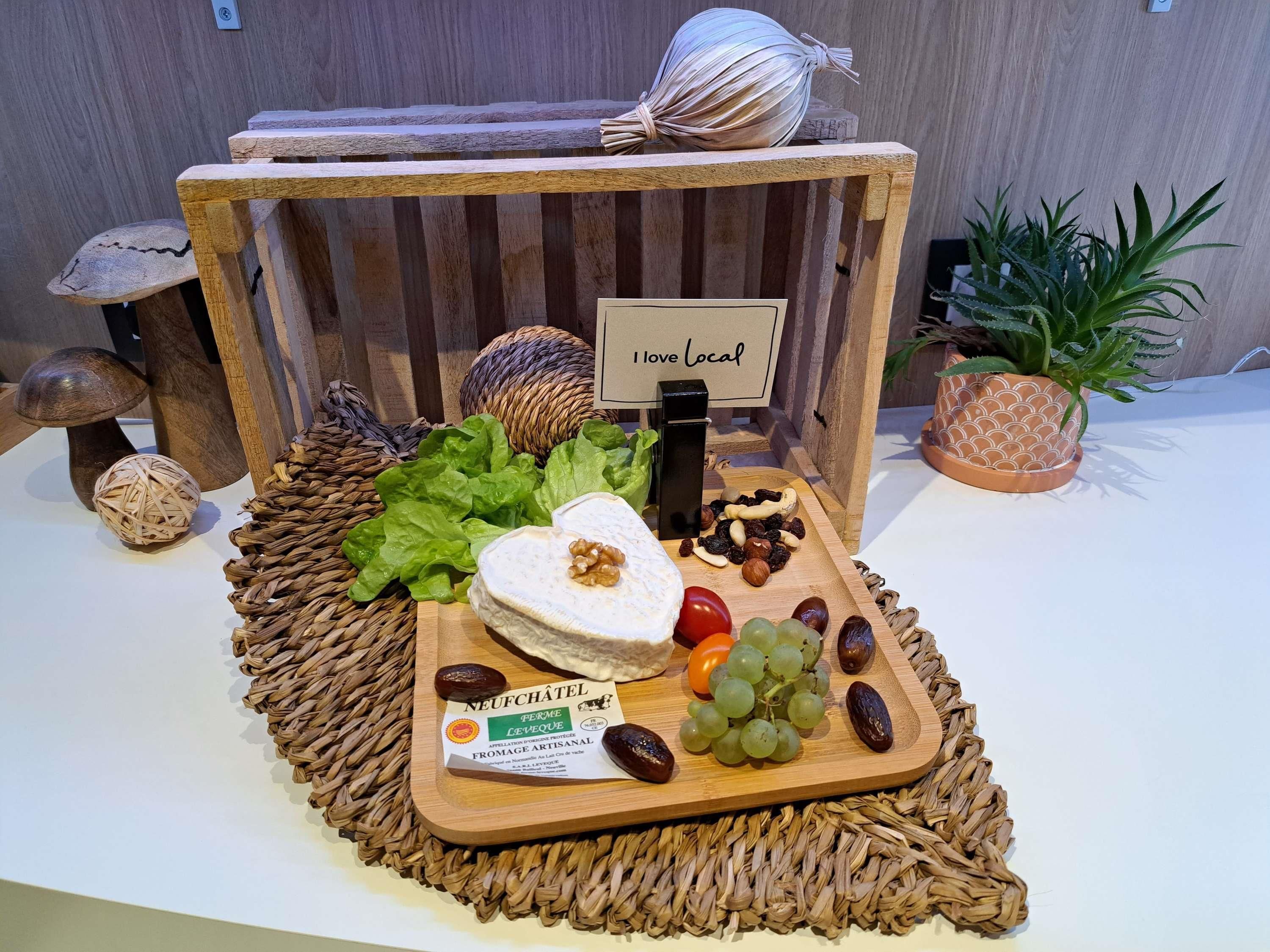 A wooden display with a sign reading 'I love Local,' featuring a cheese, grapes, nuts, and a woven placemat.