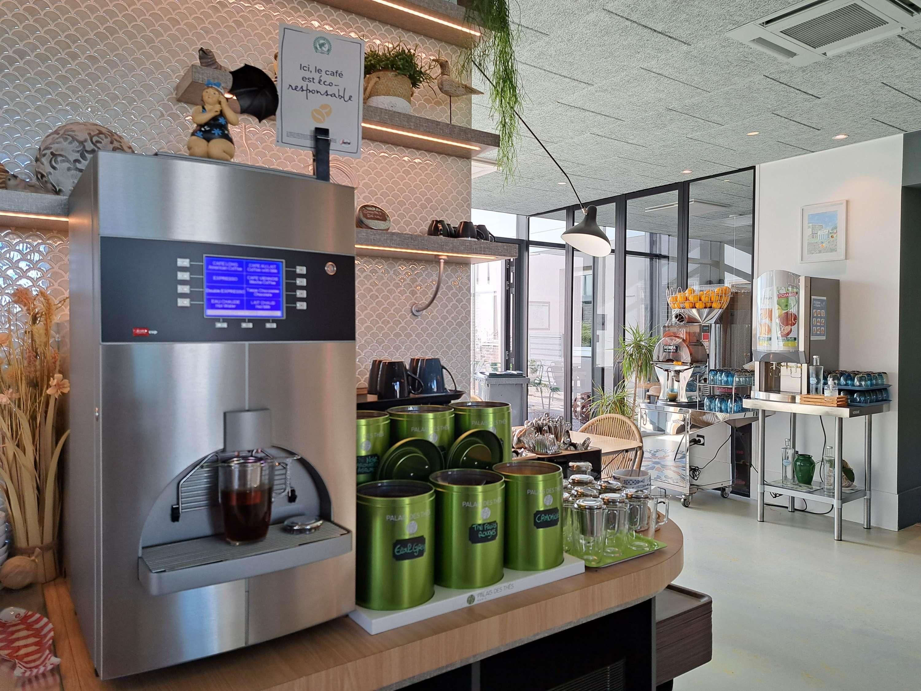 Una estación de café con una cafetera, botes verdes e indicación de que la cafetería es ecológica.
