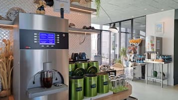 Una estación de café con una cafetera, botes verdes e indicación de que la cafetería es ecológica.